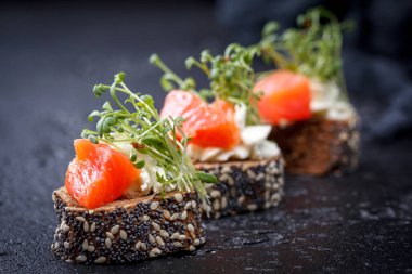 Karanlık bir arka plan üzerine somon ve peynir peynirli kanepe.