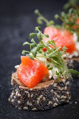 Karanlık bir arka plan üzerine somon ve peynir peynirli kanepe.