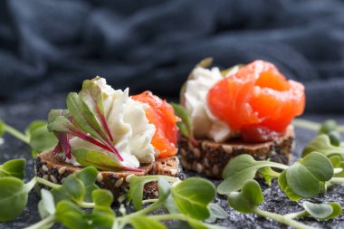 Somon, süzme peynir, zeytin karanlık bir arka plan üzerinde mikro yeşillikleri ile lezzetli kanepe. Soğuk meze.