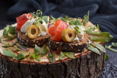 Somon, süzme peynir, zeytin karanlık bir arka plan üzerinde mikro yeşillikleri ile lezzetli kanepe. Soğuk meze.