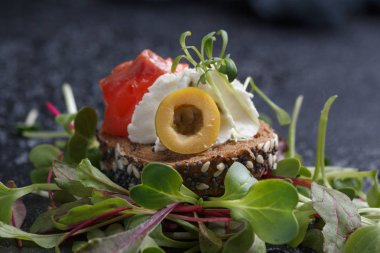 Somon, süzme peynir, zeytin karanlık bir arka plan üzerinde mikro yeşillikleri ile lezzetli kanepe. Soğuk meze.