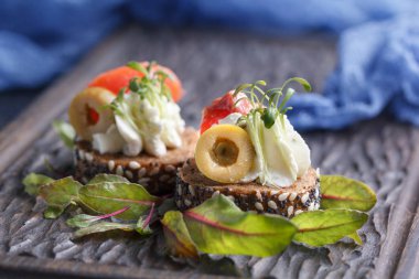 Somon, süzme peynir, zeytin karanlık bir arka plan üzerinde mikro yeşillikleri ile lezzetli kanepe. Soğuk meze.