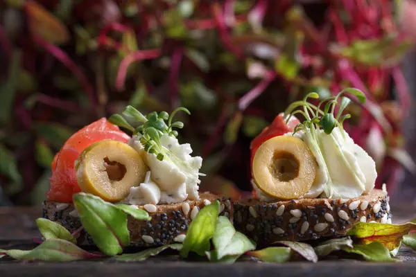 Somon, süzme peynir, zeytin karanlık bir arka plan üzerinde mikro yeşillikleri ile lezzetli kanepe. Soğuk meze.