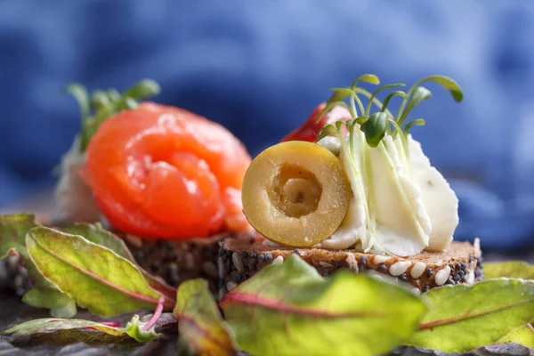 Somon, süzme peynir, zeytin karanlık bir arka plan üzerinde mikro yeşillikleri ile lezzetli kanepe. Soğuk meze.