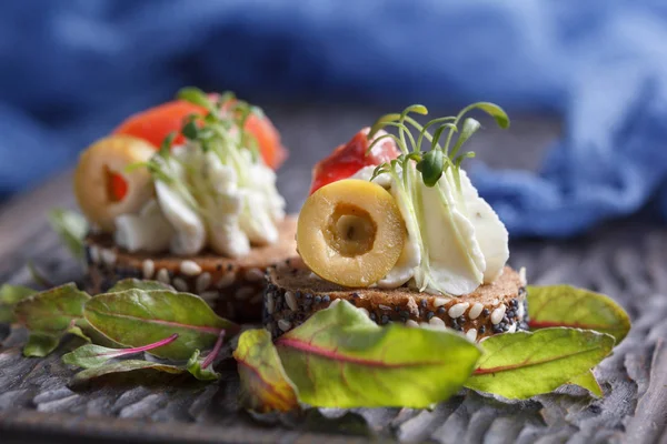 Somon, süzme peynir, zeytin karanlık bir arka plan üzerinde mikro yeşillikleri ile lezzetli kanepe. Soğuk meze.