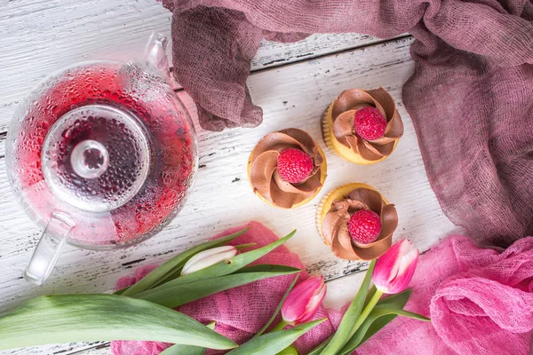 Fundo de primavera. Cupcakes e chá em uma mesa com tulipas rosa. Natureza morta com buquê fresco de tulipas. conceito de uma bebida de chá das senhoras. Chá da manhã . — Fotografia de Stock