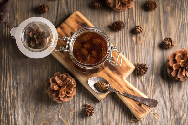 Çam kozalakları koyu ahşap arka plan üzerinde yapılmış ev yapımı reçel kavanoz.