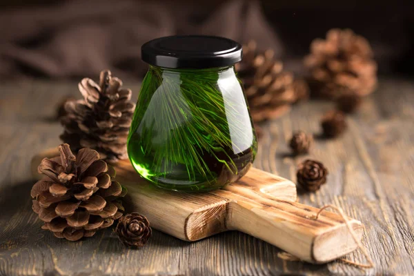 Sedir kozalakları basit ahşap arka plan üzerinde bir kurullarında bir kavanoza sedir yeşil tatlım. Kavanoz bal ile çam kozalakları.