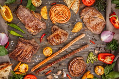 Çeşitli lezzetli ızgara et ve sosis ile sebze ahşap arka plan üzerinde. Et ve sosis adet taze sebze ile kavrulmuş lezzetli parçalarını.