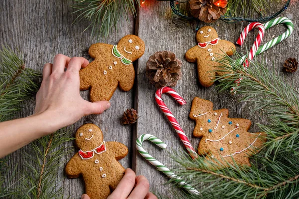 Ein Mädchen dekoriert einen Tisch zu Weihnachten. Lebkuchenmännchen. Ingwerplätzchen und Lutscher auf dem Weihnachtstisch. schöne weihnachtliche Hintergrund mit Lebkuchen Männer, Weihnachtsbäume und Schneeflocken w — Stockfoto