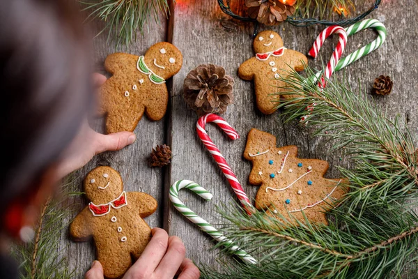 Ein Mädchen dekoriert einen Tisch zu Weihnachten. Lebkuchenmännchen. Ingwerplätzchen und Lutscher auf dem Weihnachtstisch. schöne weihnachtliche Hintergrund mit Lebkuchen Männer, Weihnachtsbäume und Schneeflocken w — Stockfoto