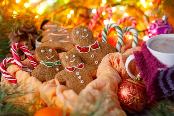 Biscuits in the form of little men for Christmas and hot drink cocoa on a background of a garland and a box in the form of a Christmas tree. Christmas tale. — Stock Photo, Image