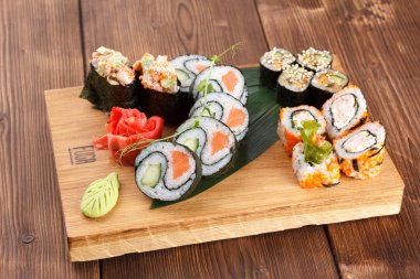 Suşi adet farklı türde tutan bir ahşap plaka. suşi ve ahşap plaka üzerinde rulo zencefil ve wasabi ile hizmet.