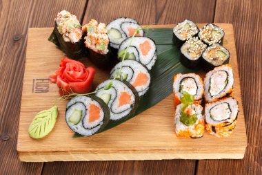 Suşi adet farklı türde tutan bir ahşap plaka. suşi ve ahşap plaka üzerinde rulo zencefil ve wasabi ile hizmet.