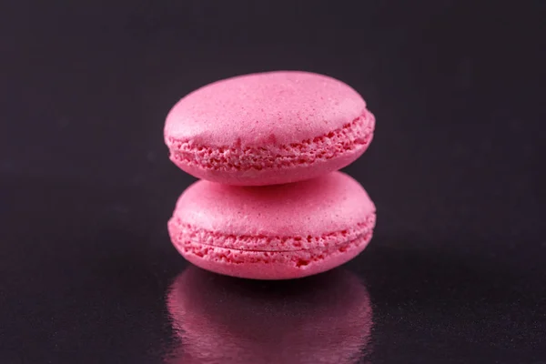 Macaroons suavemente rosa em um fundo preto . — Fotografia de Stock