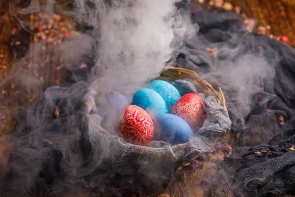 Panier avec des œufs anormalement et originellement teints sur un fond en bois dans la fumée . — Photo