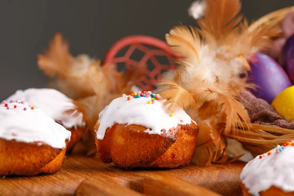 Påsk cupcakes och ägg målade i ovanliga färger dekorerade med fjädrar. — Stockfoto
