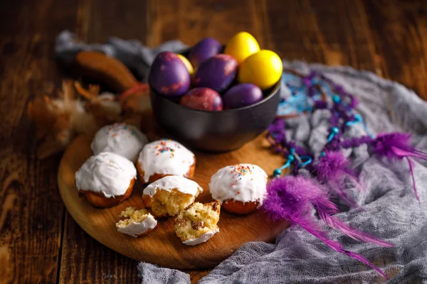 Delikat färska fruitcakes i vit glasyr och ovanligt målade ägg i en keramisk cup. — Stockfoto