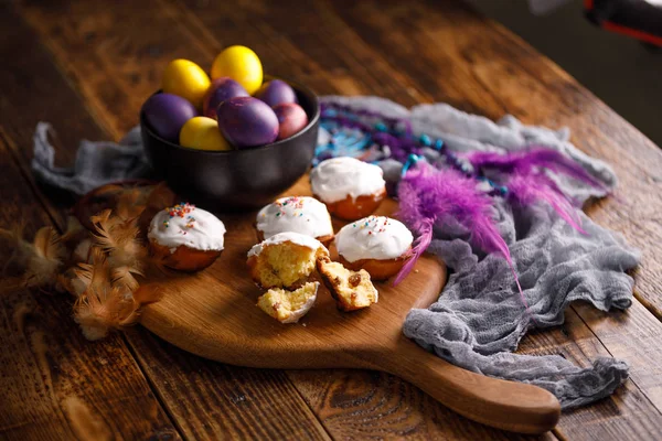 Bella natura morta pasquale con cupcake e uova dipinte insolitamente su uno sfondo di legno . — Foto Stock