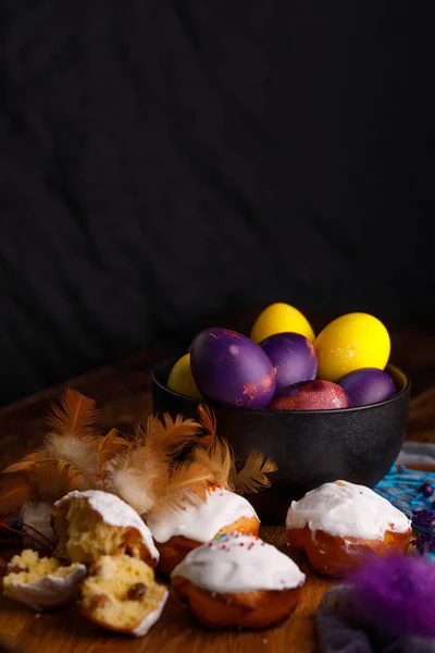 Fina muffins i vit glasyr och ovanligt målade ägg i en keramisk kopp med grejor dekorationsfjädrar. — Stockfoto