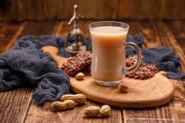 Süt ve kurabiye güzel bir tahta üzerinde cam fincan çay. Çay, bisküvi, fındık ve bir antika ceviz ile natürmort.