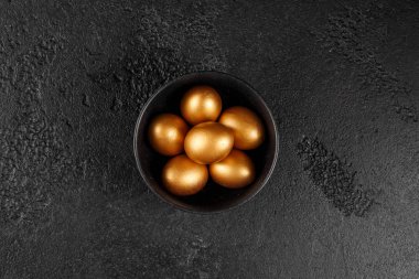 Altın yumurta siyah dokulu bir arka plan üzerinde siyah bir fincan. Paskalya yumurtaları. En iyi Manzaralı.