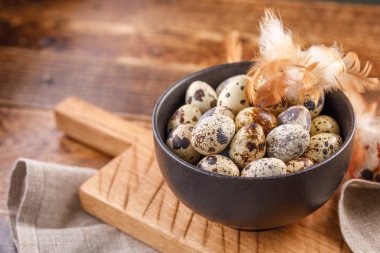 Bıldırcın yumurtası seramik kupa, peçete, ahşap tahta ahşap masa üzerinde. Bıldırcın yumurtası renkli peçete ve bir kesme tahtası ile benzer. Bir renk düzeni.