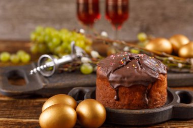 Tatlılar ve üzüm şenlikli masaya. Altın kek ve çikolata yumurta. Ahşap arka plan üzerinde bir tatil için tedavi. Paskalya natürmort.