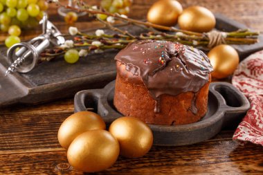 Tatlılar ve üzüm şenlikli masaya. Paskalya Çikolata pasta ve altın yumurta. Ahşap arka plan üzerinde bir tatil için tedavi.