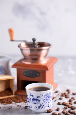 Kahve taneleri bir vintage Kahve değirmeni dışarı düşüyor. Masanın üzerinde bir güzel porselen fincan sıcak kahve. Metninizin altında bir yer ile güzel bir kahve kompozisyon.