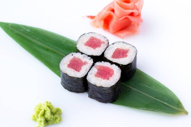 Lezzetli taze mini-ton balığı bir muz yaprağına rulo. Zencefil ve wasabi ile beyaz bir arka plan üzerinde suşi rulo. Japon menüsü.