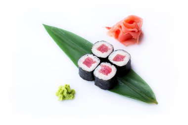 Lezzetli taze mini-ton balığı bir muz yaprağına rulo. Zencefil ve wasabi ile beyaz bir arka plan üzerinde suşi rulo. Japon menüsü.