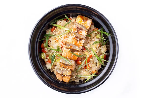 Japanese food. Rice with vegetables and fried salmon in a black bowl. Japanese food dish isolated on white background.