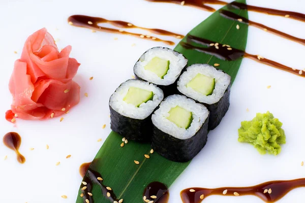 Lezzetli taze mini-salatalık ile bir muz yaprağına rulo. Zencefil ve wasabi ile beyaz bir arka plan üzerinde suşi rulo. Japon menüsü.