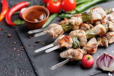 Sulu kebap şişleri domuz etinin üzerinden. Açık ateş ve siyah bir zemin üzerine taze sebze pişmiş et. Natürmort.