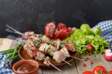 Şiş kebap şişleri üzerine bir tabak ve taze sebze ortaya koydu. Tekstil ahşap bir zemin üzerine natürmort. Yakın çekim.