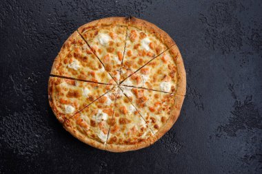 Siyah dokuda somon ve peynirle dilimlenmiş pizza. Yakın plan. Lezzetli yemek kavramı. Yukarıdan görüntüle.
