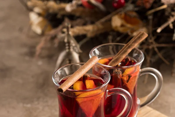 Two glasses of christmas mulled wine with oranges and spices on a textural background. Selective focus. Copy space. — Stock Photo, Image