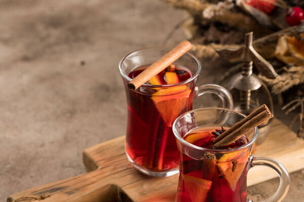 Two glasses of christmas mulled wine with oranges and spices on a textural background. Selective focus. Copy space.