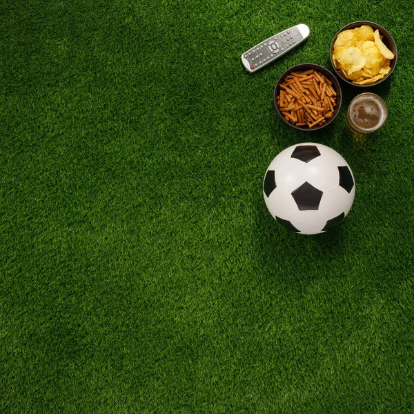 Bola de futebol em um campo verde e otomano para um fã com lanches um — Fotografia de Stock