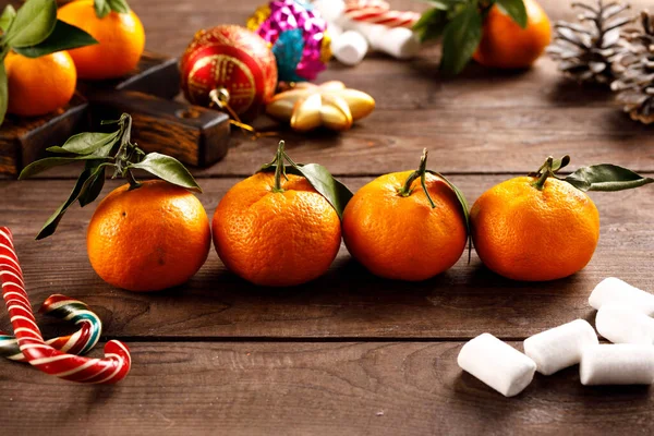 Mandarine Orangen Reihenfolge für Weihnachten und Neujahr auf Holzgrund. Obstkonzeption im Urlaub. Dekor Weihnachtsspielzeug und Süßigkeiten. — Stockfoto