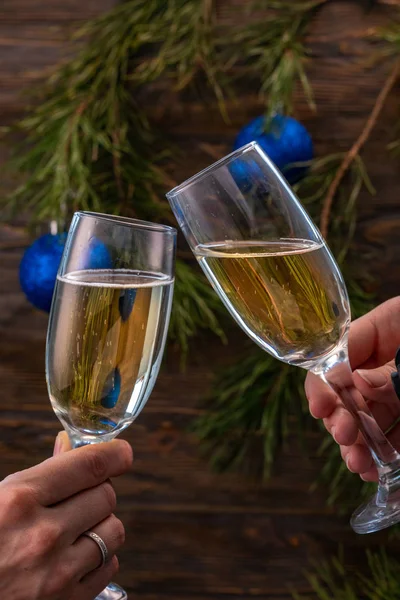 Copos de champanhe com bolhas no fundo das decorações de Natal. Os copos nas mãos de pessoas tocam-se durante uma torrada festiva. Belo cartão . — Fotografia de Stock