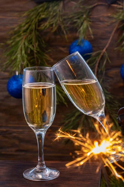 Verres de champagne avec bulles sur le fond des décorations de Noël. Les lunettes se touchent lors d'un toast festif et les étincelles brûlent magnifiquement. Belle carte . — Photo