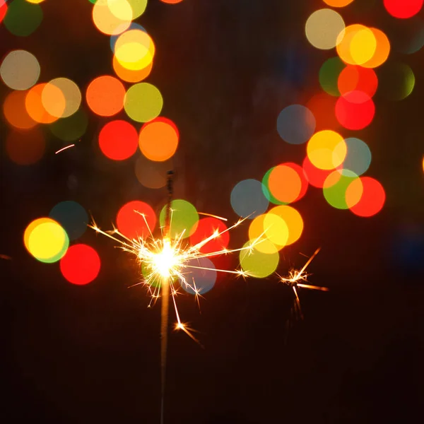 Beautiful sparklers on the background of a garland. beautiful holiday card for the New Year. — Stock Photo, Image
