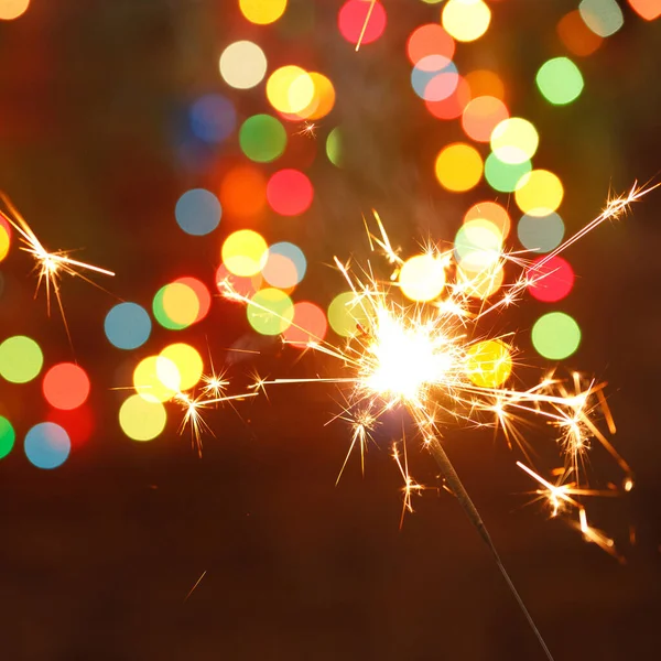 Beautiful sparklers on the background of a garland. beautiful holiday card for the New Year. — Stock Photo, Image