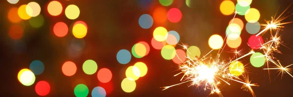 Beautiful sparklers on the background of a garland. beautiful banner for the New Year. — Stock Photo, Image