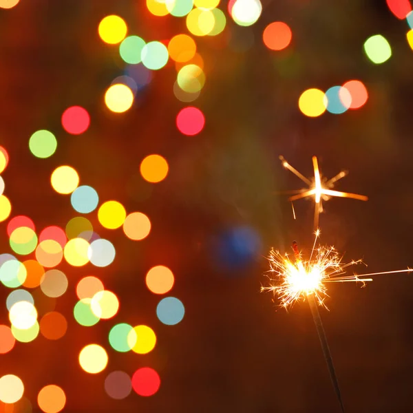 Beautiful sparklers on the background of a garland. beautiful holiday card for the New Year. — Stock Photo, Image