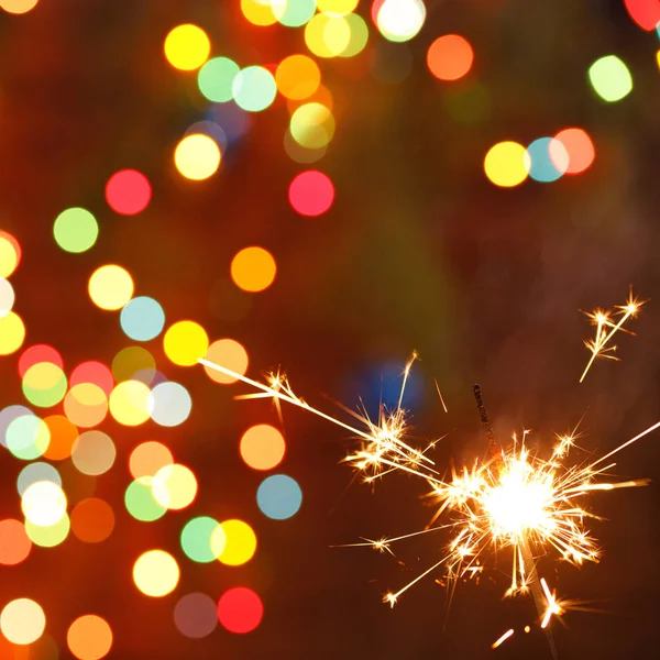 Beautiful sparklers on the background of a garland. beautiful holiday card for the New Year. — Stock Photo, Image