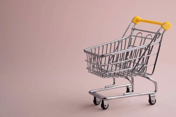 Gedraaide pushcart leeg op lichtroze achtergrond, Black Friday concept. — Stockfoto