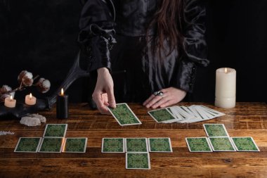 Female tells the future with playing cards. Tarot card concept on the table. Prediction of the future. Fortuneteller hands in black vestments.Psychic.
